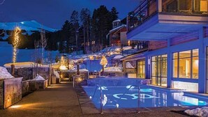 Un edificio moderno con zona de piscina, rodeado de terreno nevado y árboles.