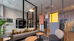 Ein modernes Interieur mit einer Couch, zwei runden Tischen, einem Sessel und einer Topfpflanze.