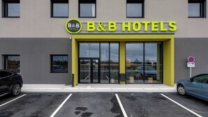 Ein Bed & Breakfast Hotel mit moderner Fassade, großem Glas Eingang und einem Parkplatz mit zwei Autos.