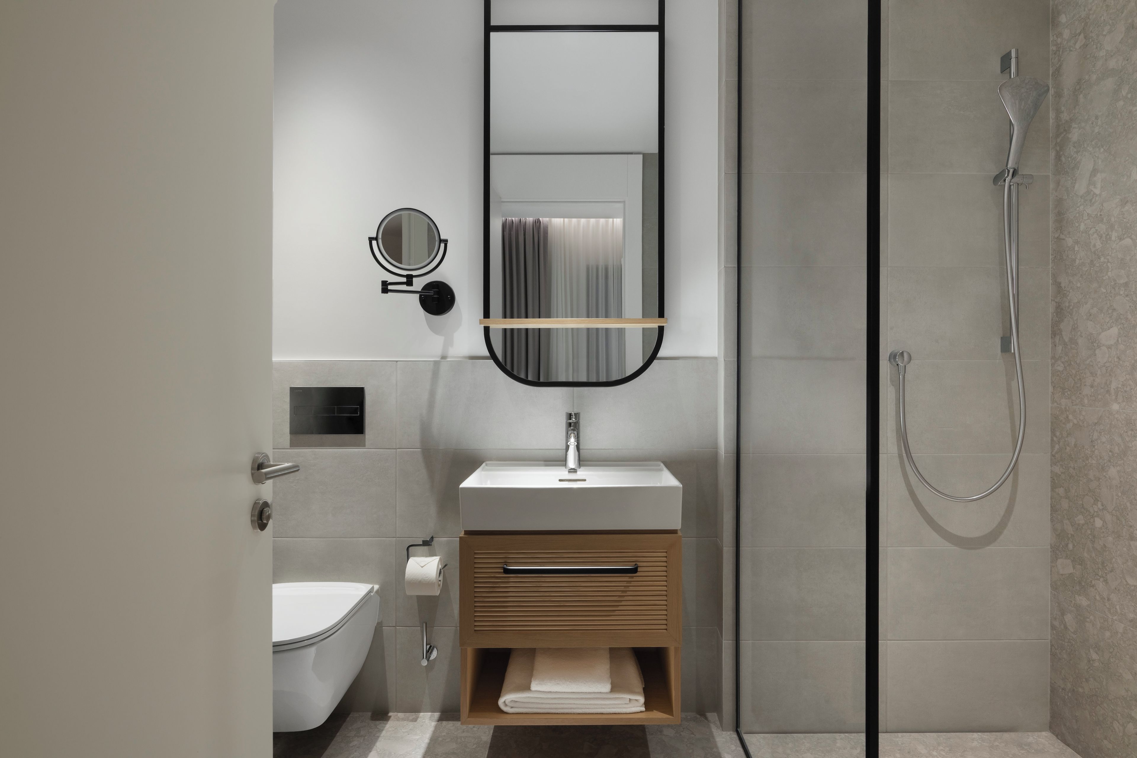 A modern bathroom with a toilet, sink, mirror, and shower.