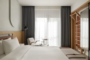 A modern hotel room with a large bed, a chair, a small table, and a wooden ladder. - Siro Porto Montenegro (Tivat)