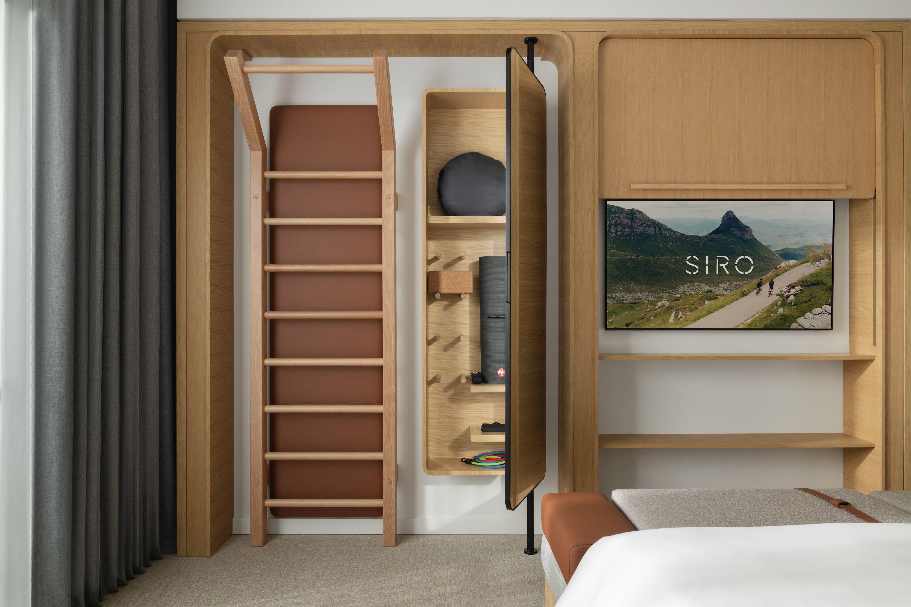 A hotel room with a wooden ladder, a flat-screen TV, and a bed.