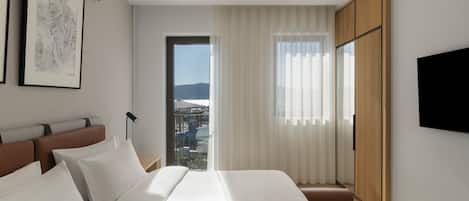 Une chambre d’hôtel moderne avec un grand lit, une vue sur la ville et un téléviseur fixé au mur.