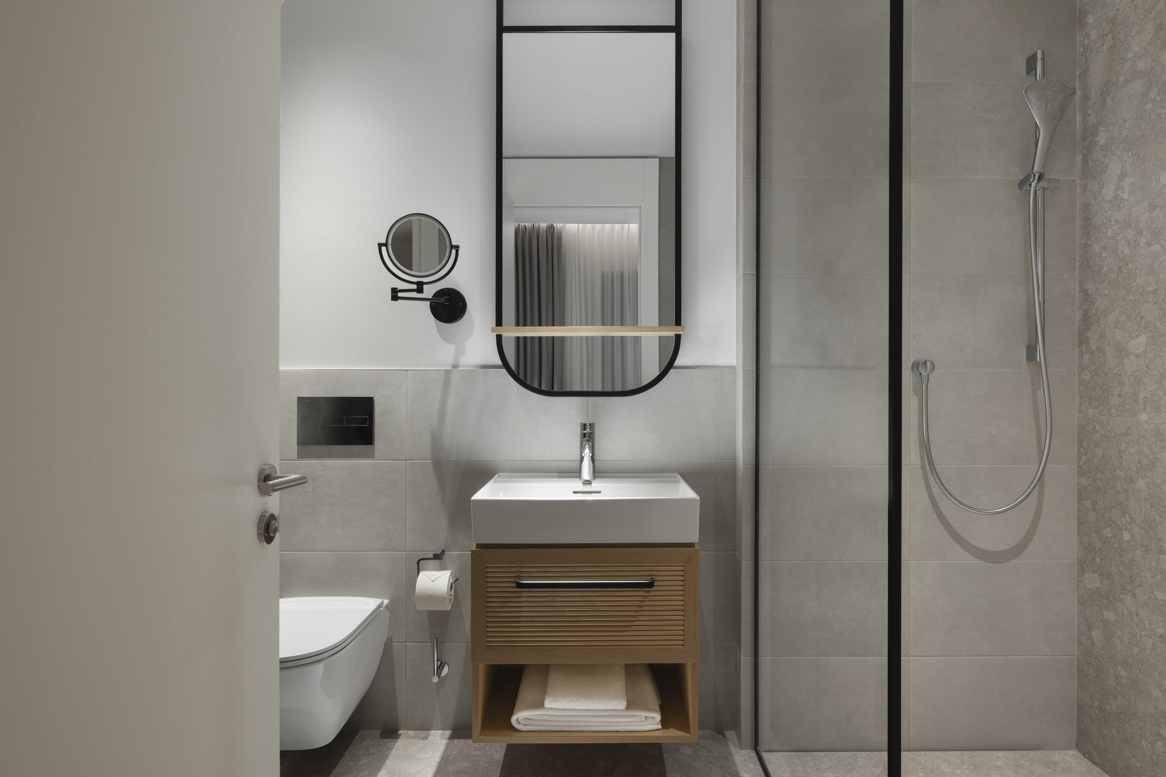 A modern bathroom with a glass shower enclosure, a white sink, a mirror, and a toilet.