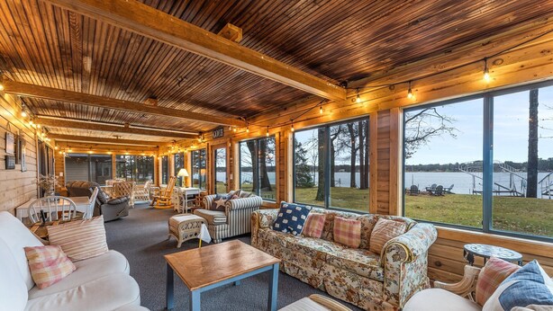 A cozy room with a wooden ceiling, large windows, and a sofa with floral upholstery. - Dock, Firepit & Cuyuna Trails at Serpent Lake (Crosby)