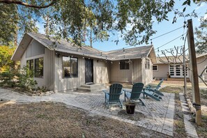 A modern house with a covered patio, two green Adirondack chairs, and a small table.