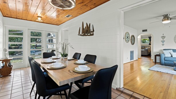 A dining area with a wooden table set for six, surrounded by black chairs. - Doras Dream, 4 Bedrooms, Sleeps 12, Downtown (Mount Dora)