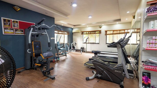 A gym with exercise equipment, a treadmill, and a fan. - Idiroko estate - Green, Beautiful, Quiet and Central (Lagos)