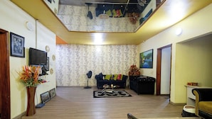 A spacious living area with a high ceiling, a black sofa, a wooden coffee table, and a decorative plant. - Idiroko estate - Green, Beautiful, Quiet and Central (Lagos)
