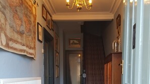 A hallway with wooden flooring, a radiator, a map on the wall, and a chandelier. - Afallon Townhouse (Dolgellau)