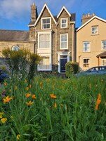 A row of two-story houses with a garden in the foreground.