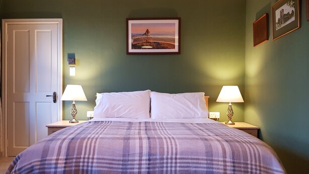 A bedroom with a bed, two bedside tables with lamps, a door, and a framed picture on the wall. - Afallon Townhouse (Dolgellau)