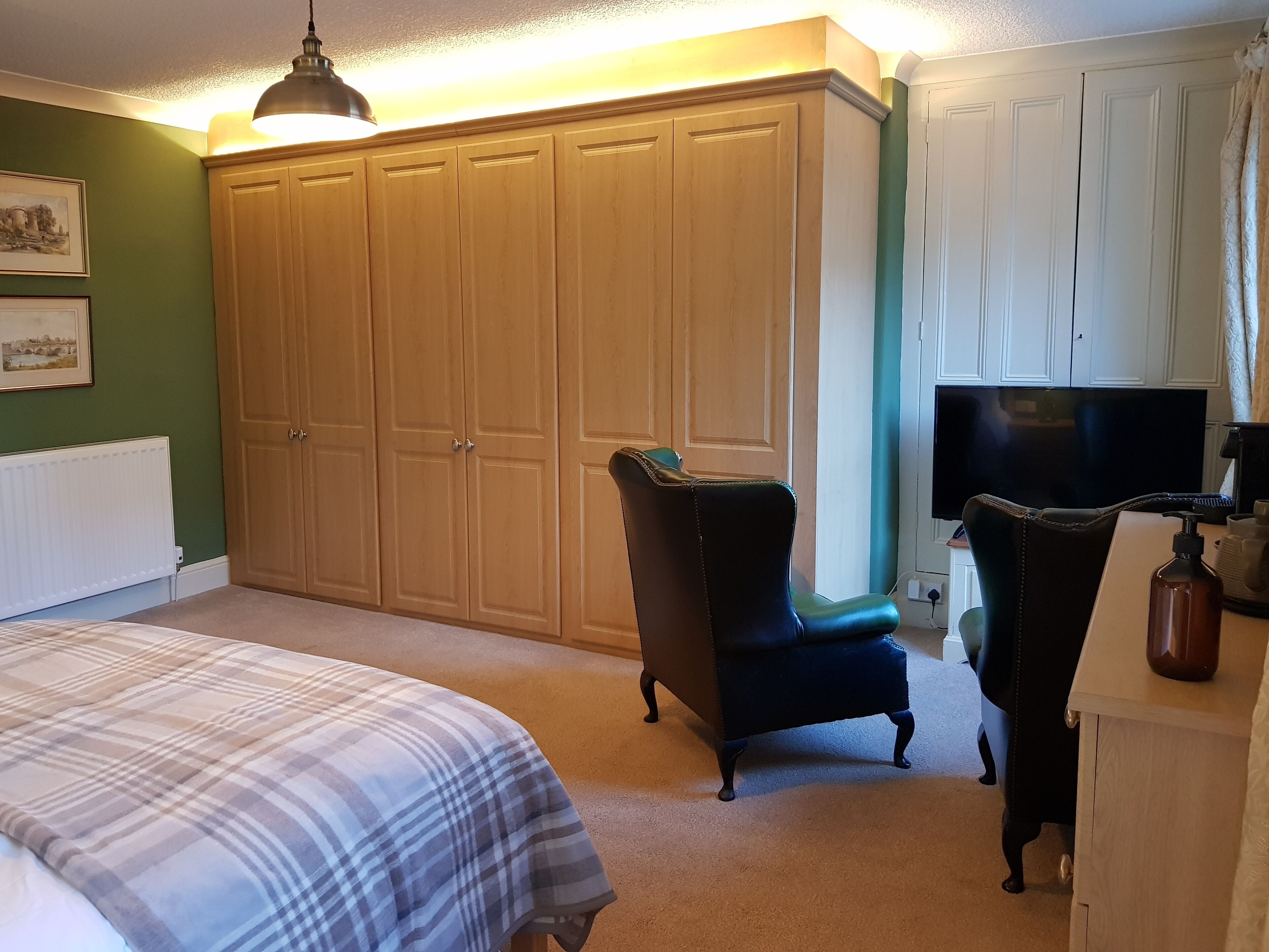 A bedroom with a bed, a wardrobe, a chair, and a television.