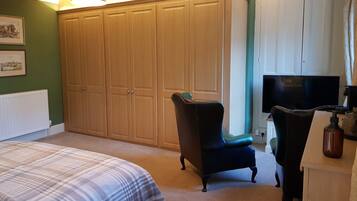A bedroom with a bed, a wardrobe, a chair, and a television.