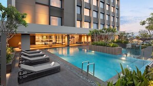 A modern hotel with a rooftop pool, lounge chairs, and a well-lit interior. - Mercure Madiun (Madiun)