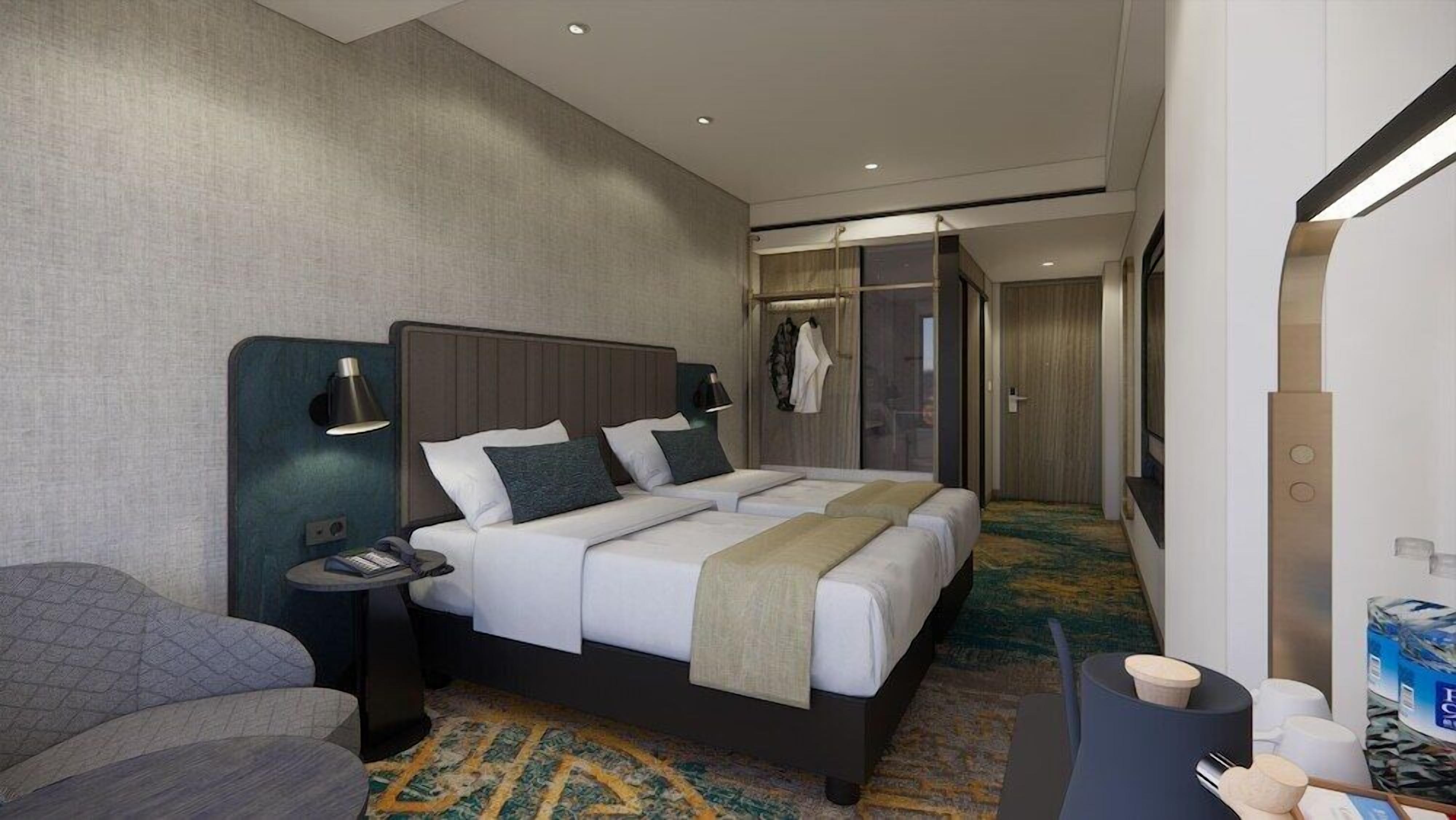 Habitación de hotel con cama, mesitas de noche, escritorio con silla, armario y baño con ducha e inodoro.