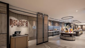 A reception area with a counter, a wall-mounted sign, and a buffet setup with various food items. - Mercure Madiun (Madiun)