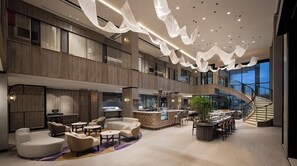 Un hall espacioso con bar central, zonas de estar y una escalera que lleva a los pisos superiores.