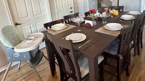 Ein Esszimmer mit einem rechteckigen Tisch, gedeckt für vier Personen, umgeben von Holzstühlen.