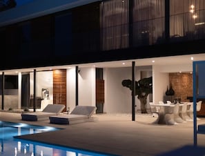 Et moderne poolområde med liggestole og et spiseområde.