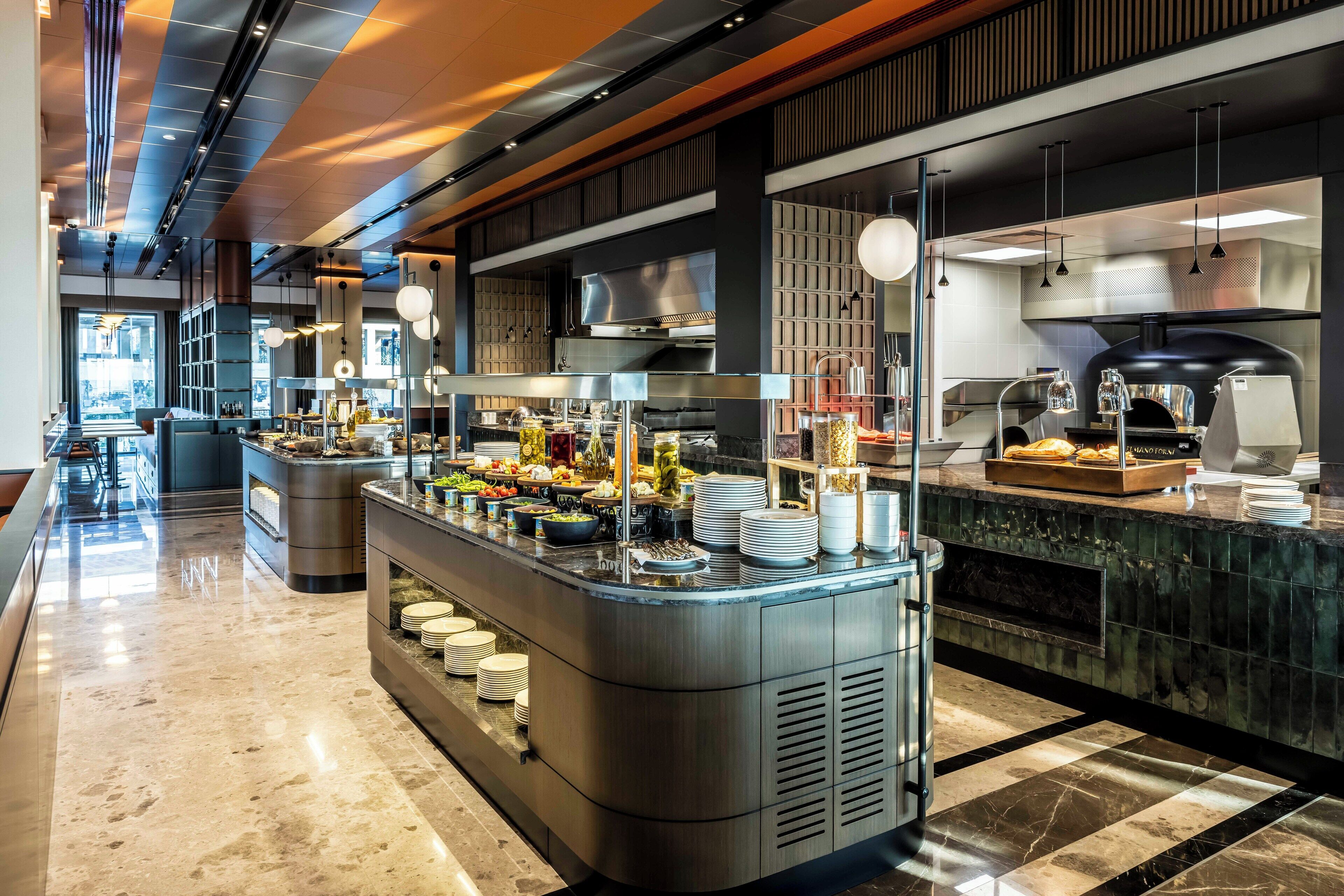 Una moderna presentación de buffet con una variedad de alimentos, piso de mármol e iluminación contemporánea.