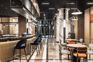 Eine moderne Hotelhalle mit Barbereich, Sitzgelegenheiten und einer Rezeption.
