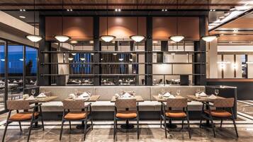 Un restaurante moderno con una barra alargada, asientos acolchados e iluminación colgante.
