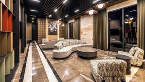 Un interior moderno con un sofá modular curvo, una mesa de centro redonda y sillones estampados.
