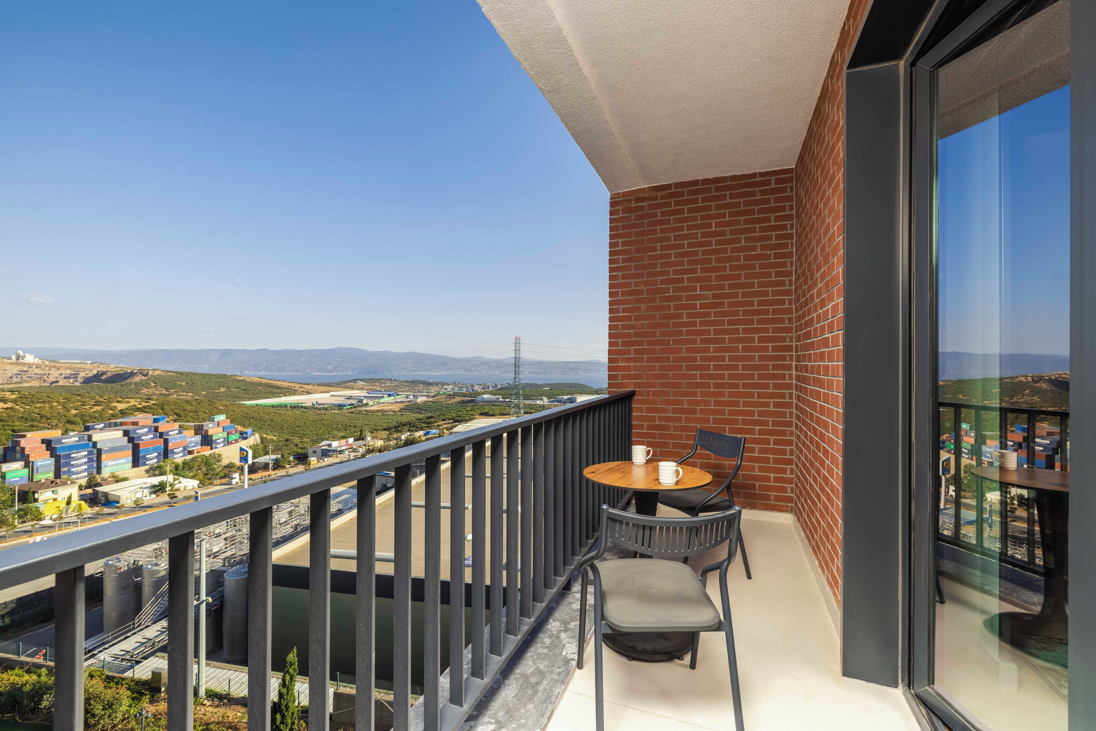 A balcony with a view of a port and distant mountains.