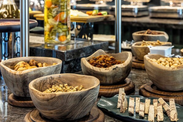 A buffet with various food items in wooden bowls, including nuts, dried fruits, and other snacks. - Golden Tulip Gebkim Kocaeli (Dilovasi)