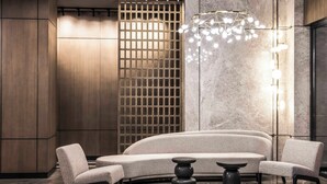 Un interior moderno con un sofá curvo, dos sillones, una mesa redonda y una lámpara decorativa.