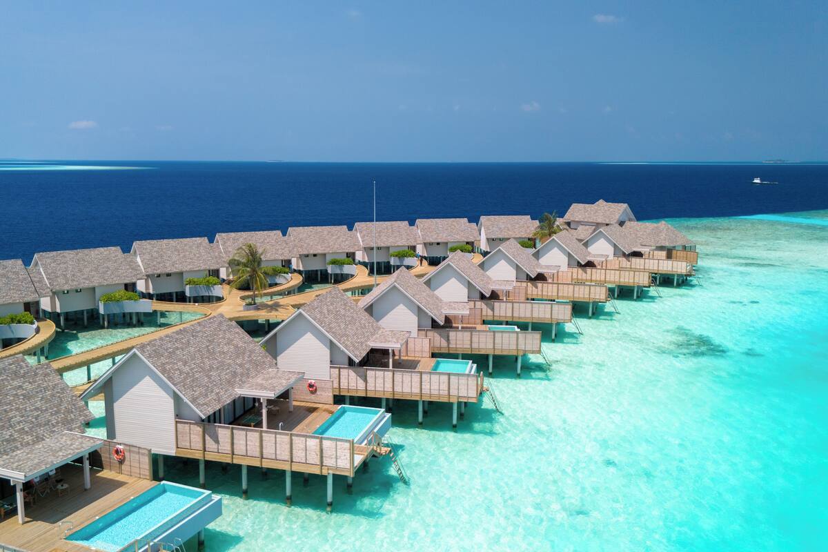 Overwater bungalows with swimming pools, connected by walkways, and surrounded by turquoise waters.
