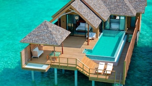 Un bungalow en bois construit sur pilotis, doté d’une piscine, de chaises longues et d’une terrasse en bois.