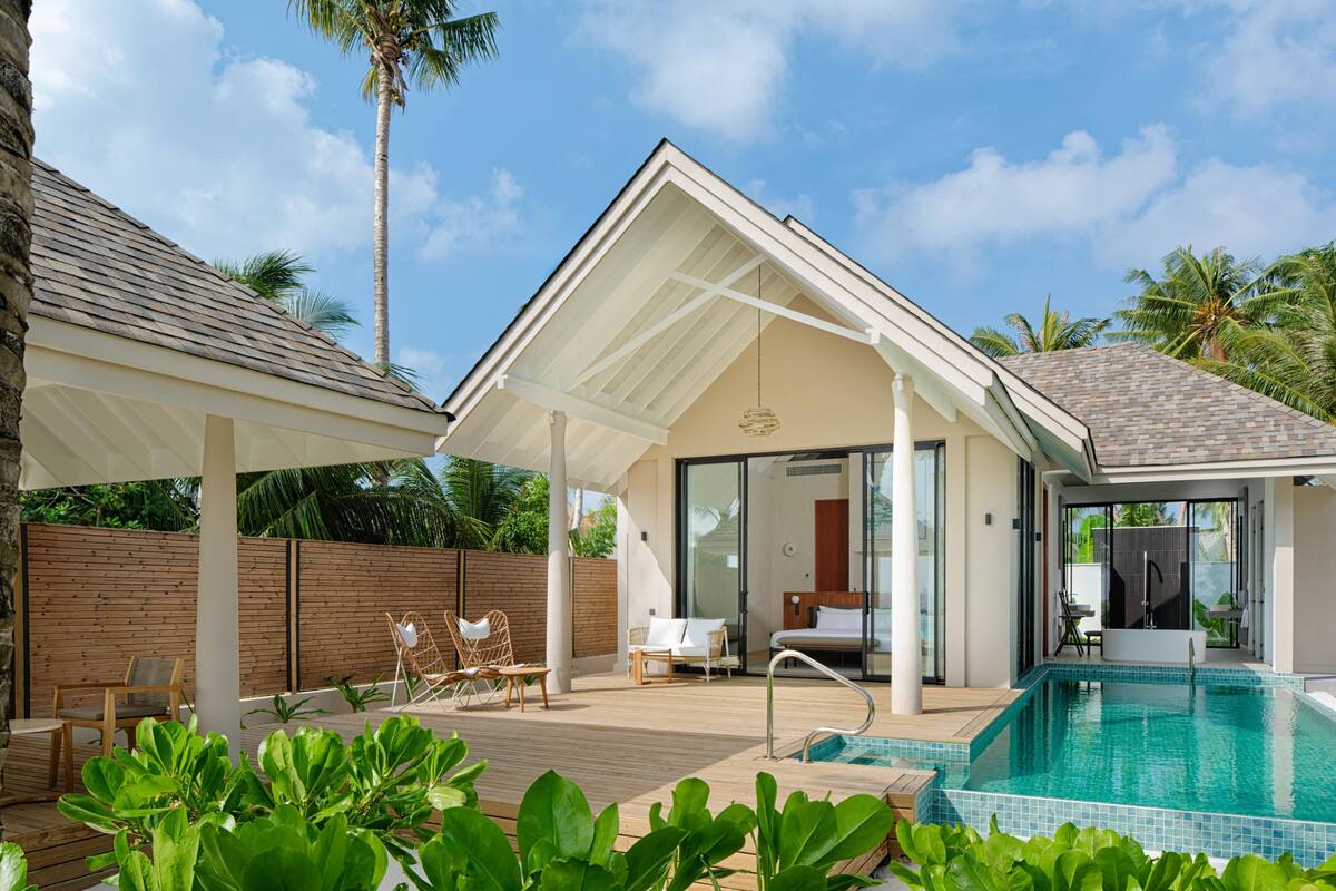 A modern villa with a swimming pool, a covered patio, and a bedroom with a large window.