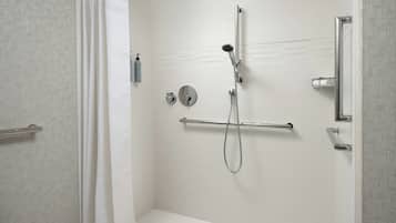 Una ducha moderna con cabezal de ducha de mano y grifo empotrado, barra para toallas y dispensador de jabón.