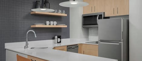 A modern kitchen with a white countertop, stainless steel appliances, wooden cabinets, and a built-in dishwasher.