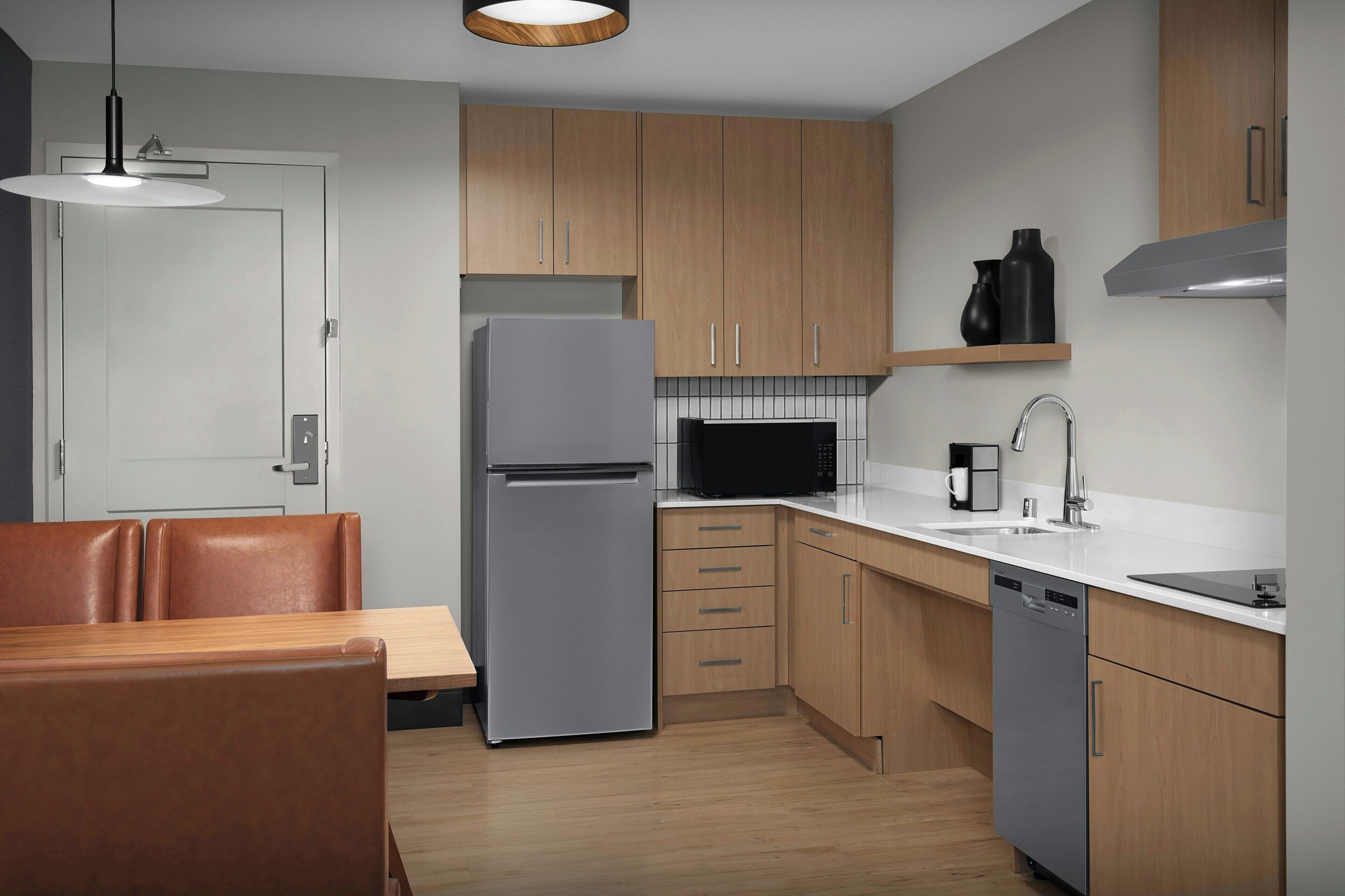 A modern kitchen with wooden cabinets, a stainless steel refrigerator, a microwave, and a dishwasher.