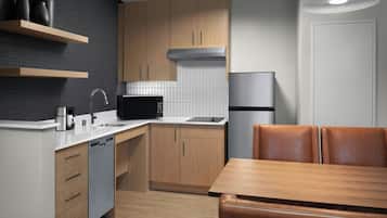 A modern kitchen with wooden cabinets, a stainless steel dishwasher, a black microwave, and a refrigerator.