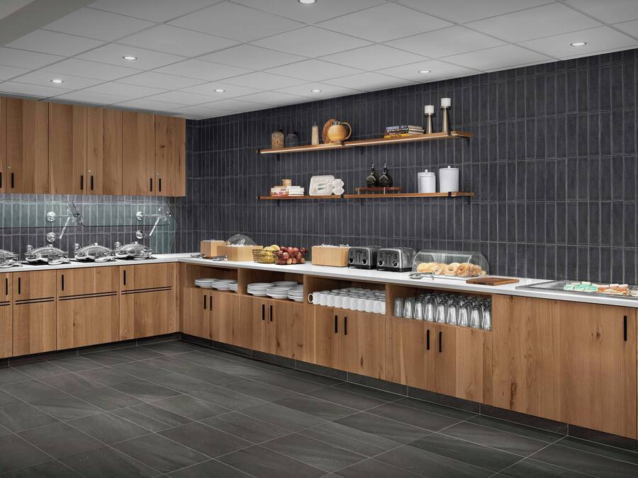 A modern kitchen with wooden cabinets, dark tiled backsplash, and various kitchen items on shelves.