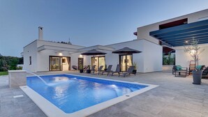 Une maison moderne dotée d’une piscine, d’un espace salon extérieur et d’un patio couvert.