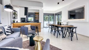 Un salon moderne comprenant un canapé, une table basse et un coin repas avec des chaises.