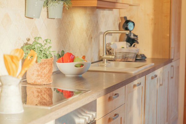A kitchen with a marble countertop, a sink, a stove, and a potted plant.