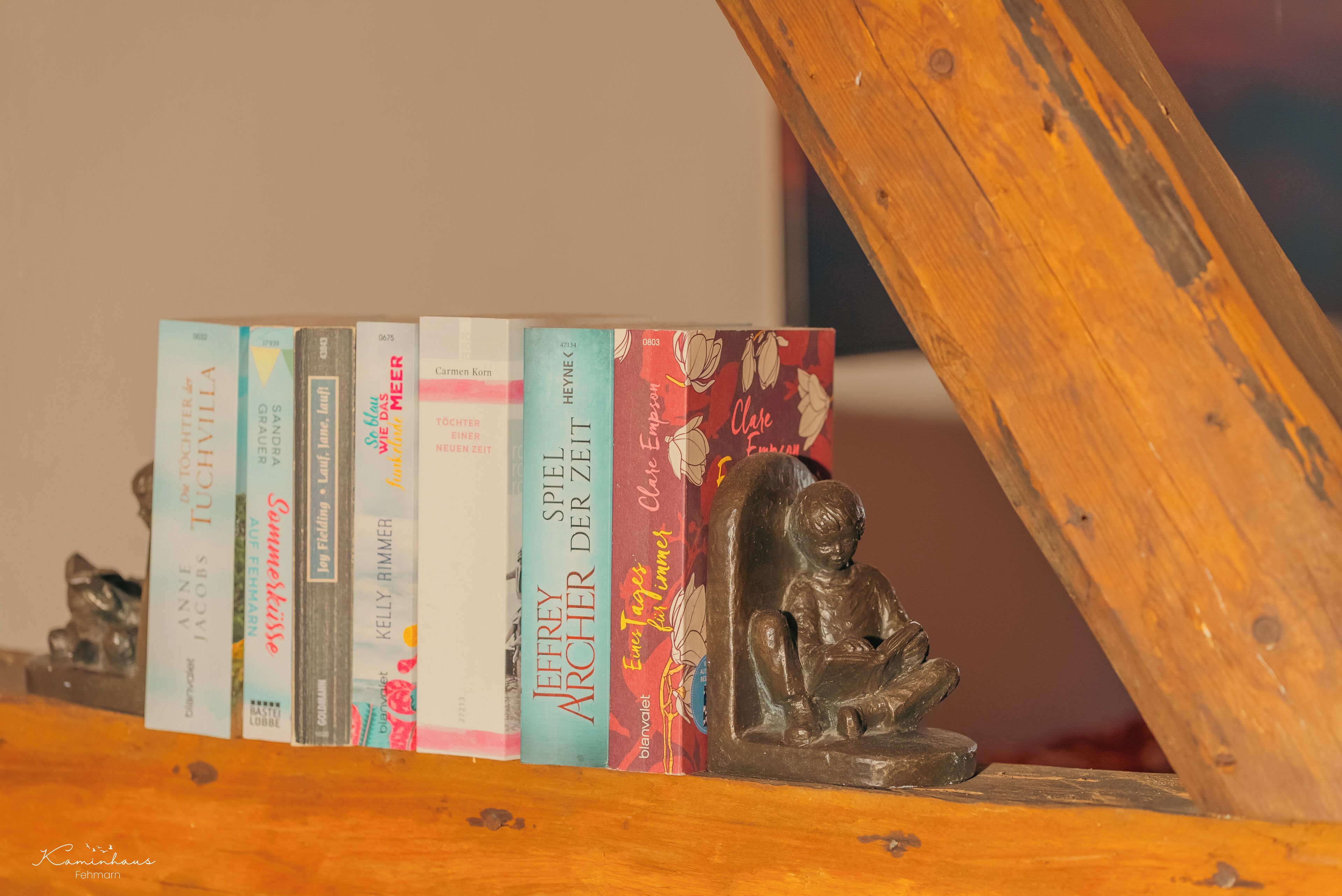 Una estantería de madera con libros y una pequeña estatua.