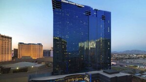 Ein modernes Hochhaus-Hotel mit Glasfassade, genannt 'Hilton Grand Vacations', mit Poolbereich und Blick auf die umliegende Stadtlandschaft.