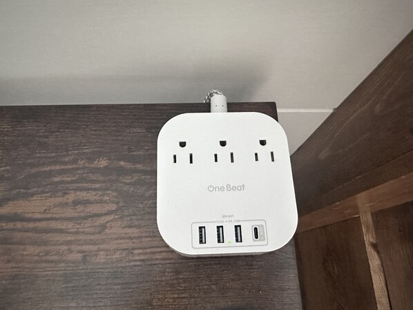 Una regleta inteligente OneBeat blanca con varios puertos USB montada sobre una superficie de madera.