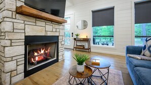 Una sala de estar con chimenea de piedra, un televisor de pantalla plana montado encima y un sofá azul.