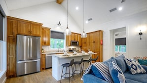Una cocina moderna con armarios de madera, electrodomésticos de acero inoxidable y una isla central con taburetes de bar.