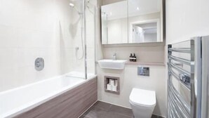 Et moderne badeværelse med badekar, toilet og håndvask.
