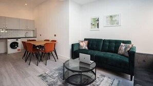 A modern apartment with a dining area, a green sofa, and a laptop on a coffee table. - PBC | Studio Apt in Richmond (RICH3) (London)
