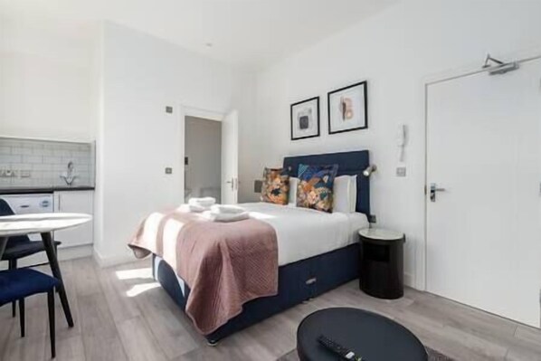 A modern bedroom with a bed, bedside table, and a small round table.